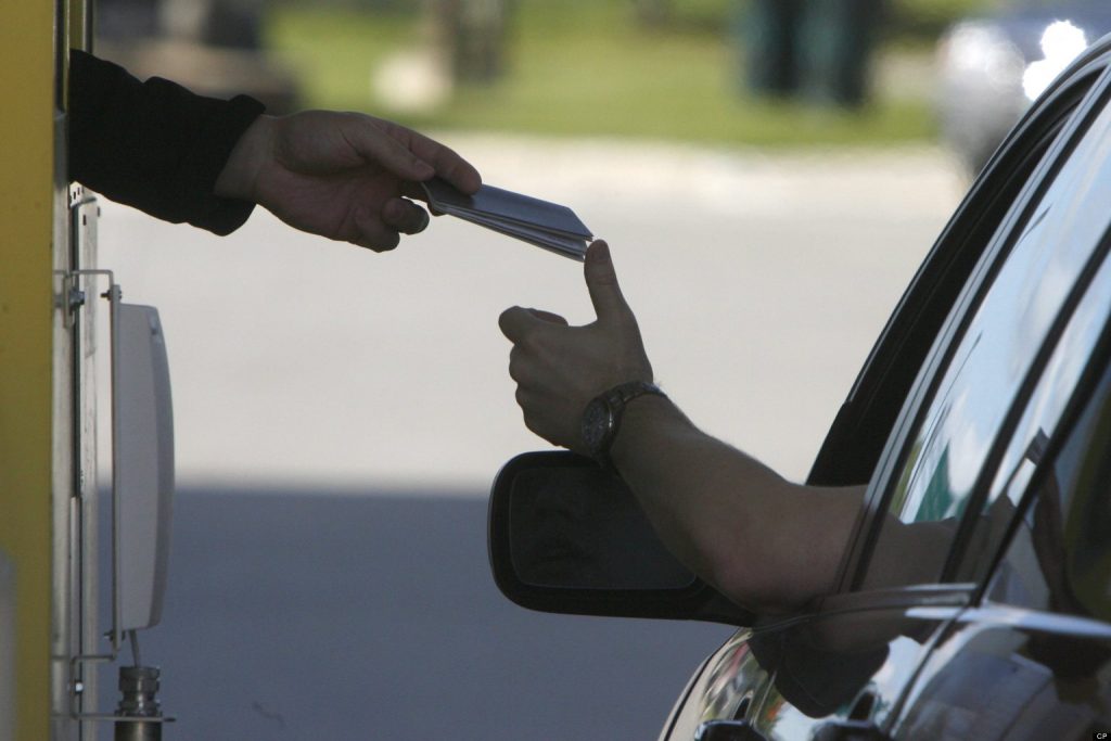 FILE- In this June 1, 2009 file photo, a driver hands his passport to a border agent at the U.S. border crossing in Highgate Springs, Vt. A Department of Homeland Security proposal to study charging a fee for people entering the United States by land from Canada and Mexico is being criticized by members of Congress from Vermont and upstate New York. Vermont's two United States senators, Rep. Peter Welch and New York Rep. Bill Owens all say charging a fee to people entering the country by land would hinder commerce and the long-established practice of crossing easily. (AP Photo/Toby Talbot)